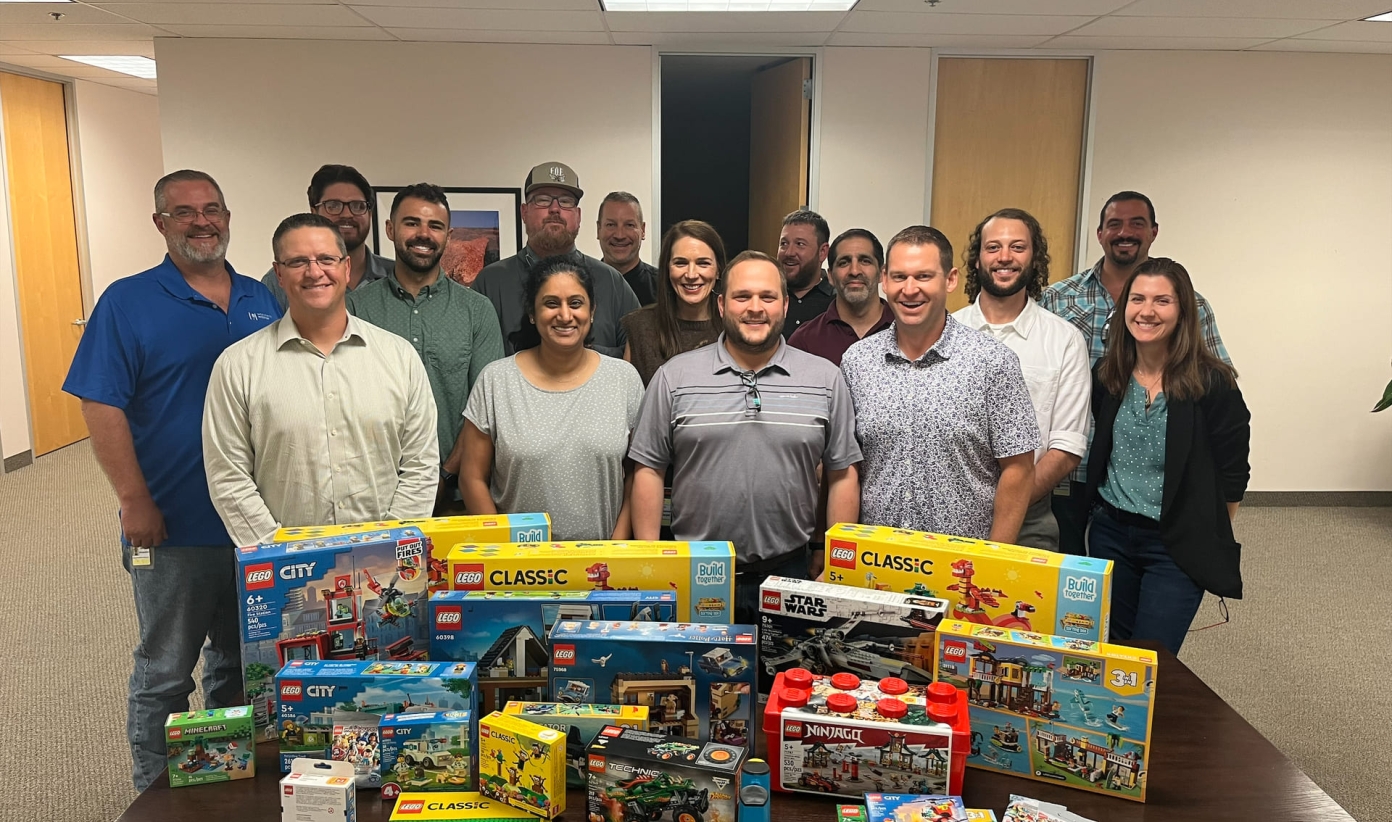 Group of people standing behind a table covered with Lego boxes